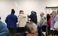 Das Buffet ist eröffnet! Die Besucher*innen stehen an den Buffettischen und nehmen sich etwas zu essen.