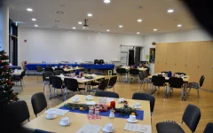 Der Georg-Gottlob-Saal ist weihnachtlich geschmückt. Im Saal stehen 8er-Tische, die mit Tannenzweige, Kerzen und Keksen dekoriert sind.