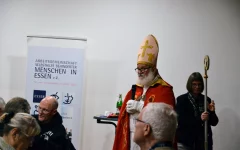Besuch vom Nikolaus. Er trägt einen Bischofsumhang und einem Hirtenstab. 