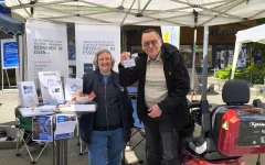 Christiane Terveen und Peter Konrad lächeln am Infostand der AGSBM stehend in Richtung Kamera.&nbsp;
