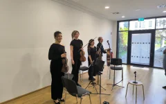 Bei großem Applaus stehen die Musiker*innen lächelnd nach dem Konzert vor den Besucher*innen.&nbsp;