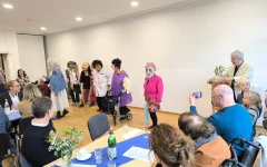 Alle Künstler*innen stehen gemeinsam vorne. Sie&nbsp;tragen verschiedene bunte Masken und Perücken. Der Drehorgel-Musiker trägt keine Maske.