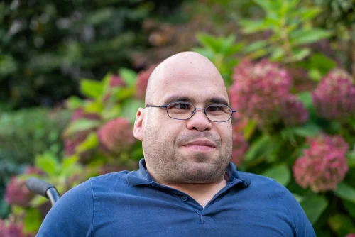 Marcel Preuß&nbsp;lächelt in die Kamera. Er trägt eine Brille und ein&nbsp;blaues Poloshirt.