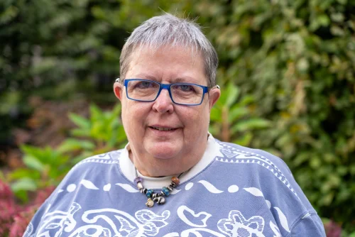 Ingrid Graumann lächelt in die Kamera. Sie trägt eine blaue Brille und ein blau-weiß gemustertes Shirt.&nbsp;